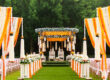 An Indian wedding mandap decorated with yellow and white flowers on an open lawn