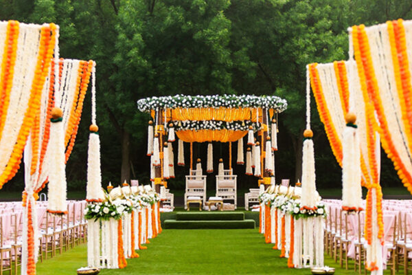 An Indian wedding mandap decorated with yellow and white flowers on an open lawn