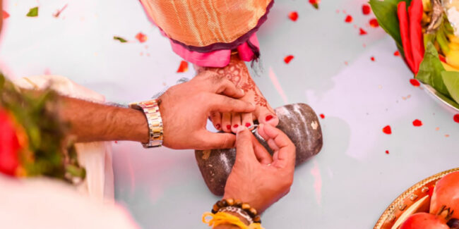 A Tamil wedding Groom wearing Toe ring or metti or minchi to the bride a tamil wedding ritual.