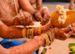 A bride securing a traditional kaapu, a Tamil Brahmin wedding ritual, around her wrist.